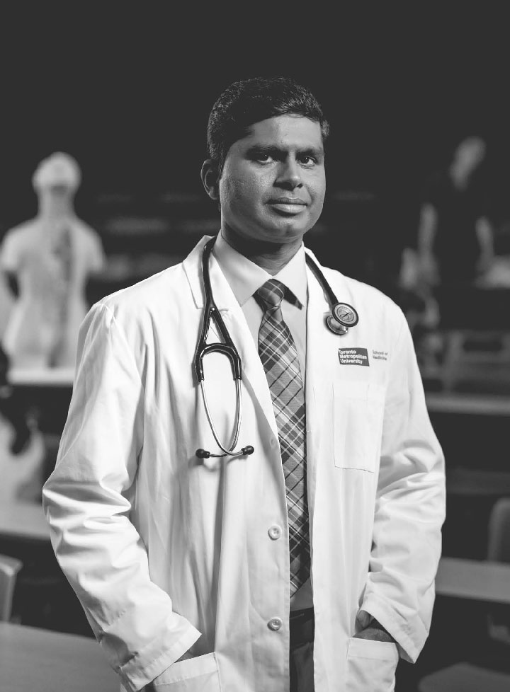 A male doctor in a white coat with stethoscope around his neck