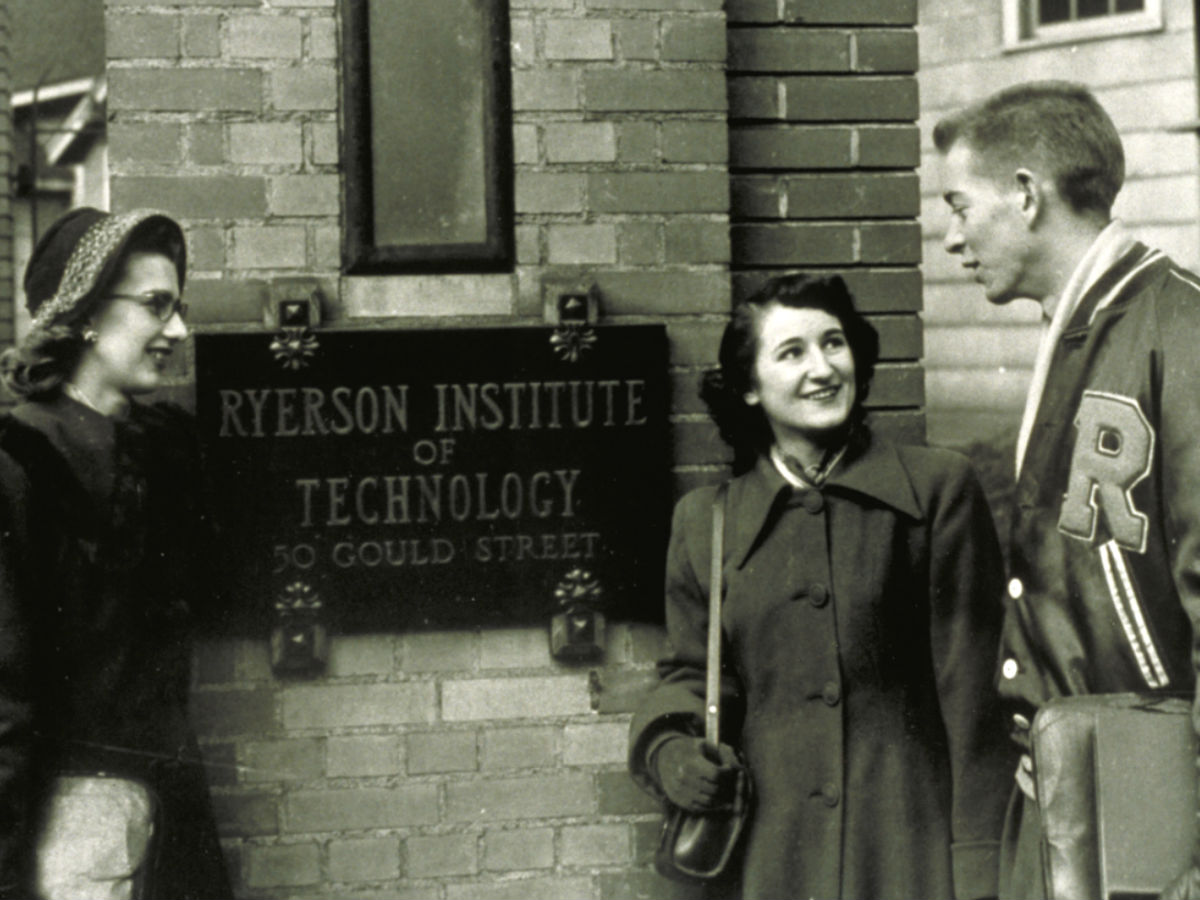 A black and white historical photo of students in front of the main building.