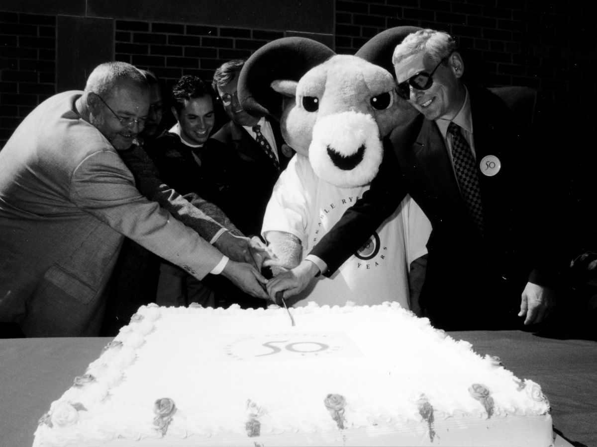 A black and white historical photo of City Councillor Kyle Rae (left) and President Claude Lajeunesse (right) celebrating the university's 50th anniversary