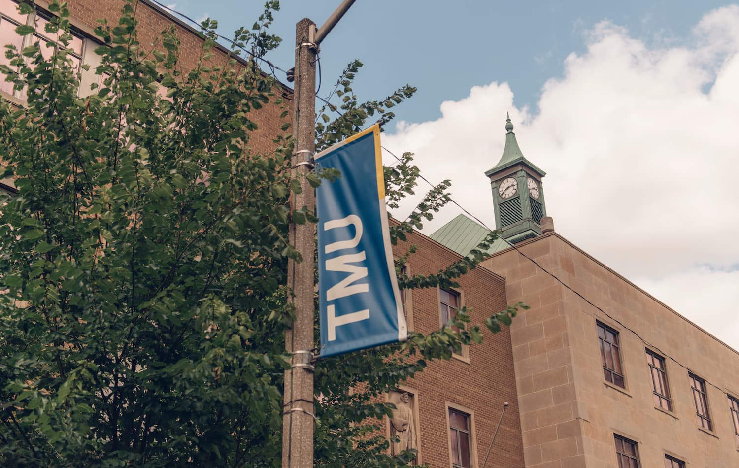 a banner on a light pole that reads "TMU" on the TMU campus
