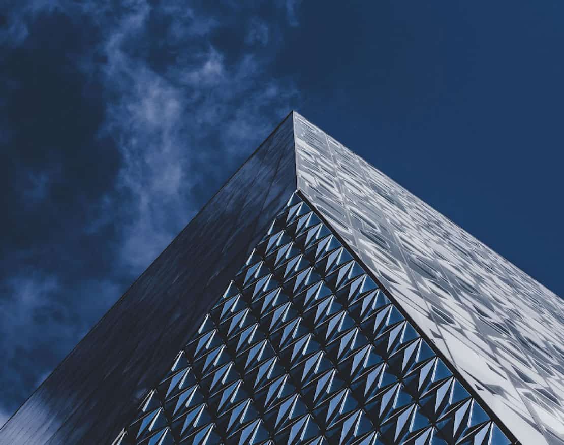 The top corner of TMU's Student Life Centre, featuring three of its unique geometric faces contrasting against a dark blue sky.