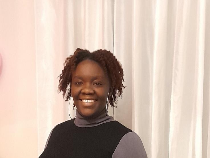 Woman smiling in front of a white curtain background.