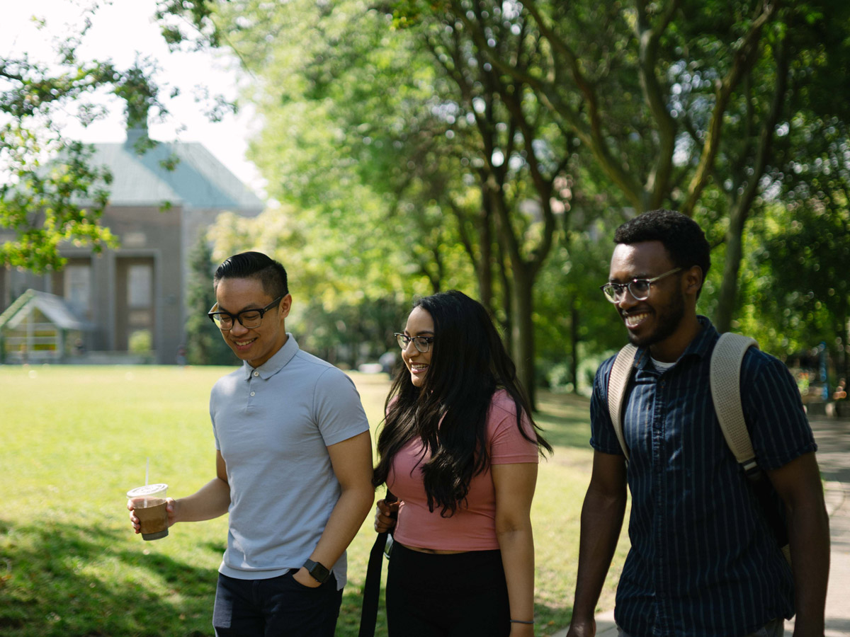 Students with coffee walk through the Quad on a sunny day.