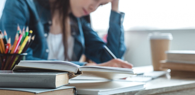Student studying tensely on a desk full of with books and notebooks