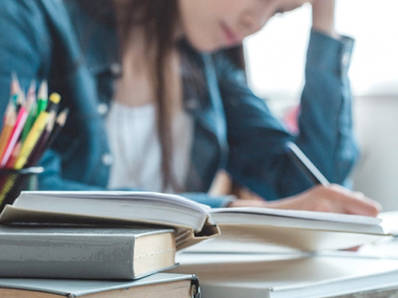 Student studying tensely on a desk full of with books and notebooks