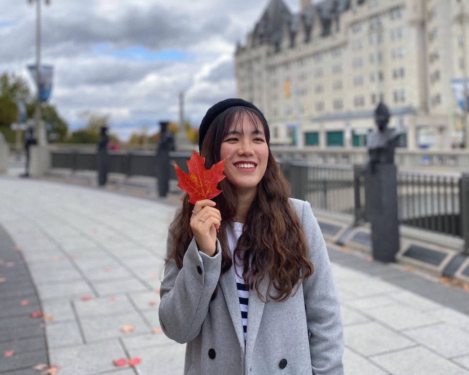 portrait of Vivian L., holding a red maple leaf in fall attire