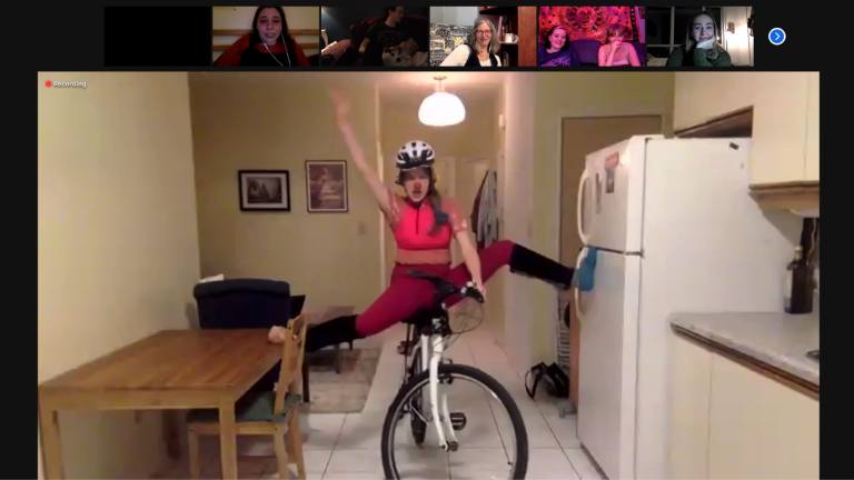 A zoom video screenshot oof Clown Anna on a bike in their kitchen space