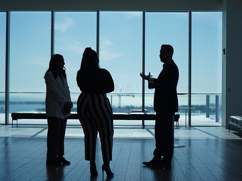 Three individuals have a conversation at a conferencee.