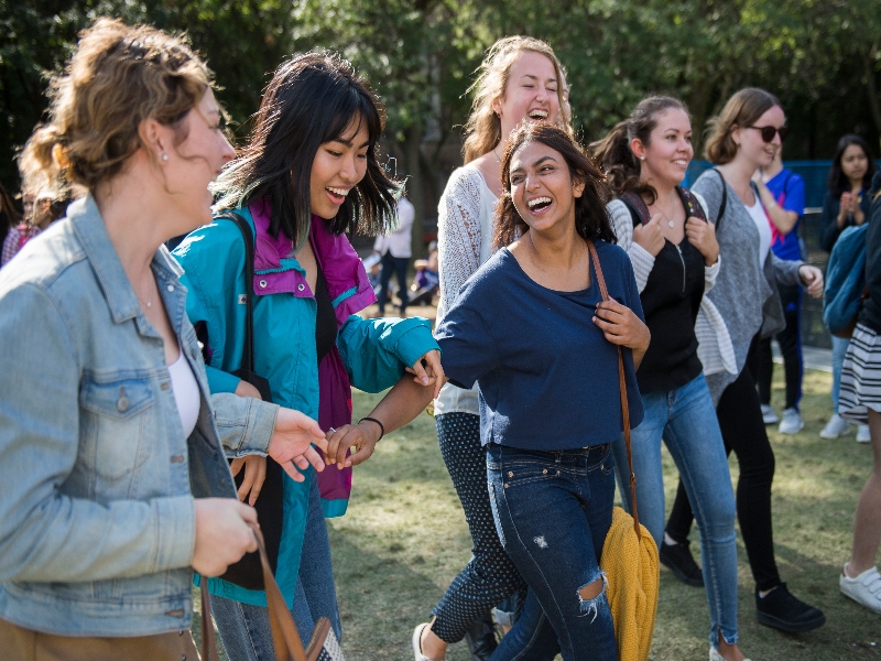 A group of students laughing and talking while walking together 