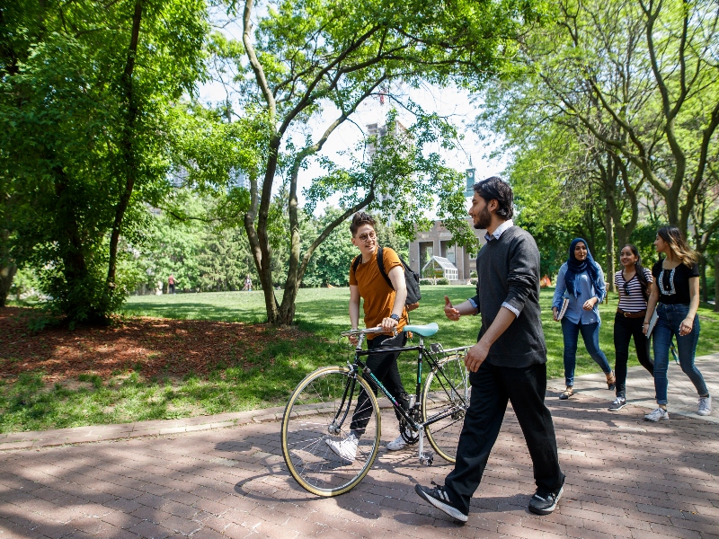 Two students walking with a bike across Kerr Hall