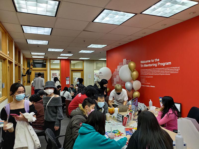People chatting and gathering in the Tri-Mentoring Program offices during one of their celebrations.