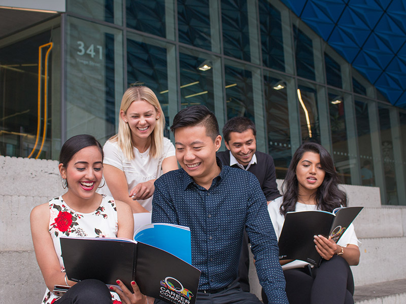 A group of students sit outside the Student Learning Centre while looking through Career Checkpoint booklets.