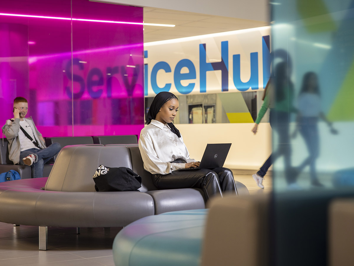 A student works on her laptop in front of the ServiceHub.