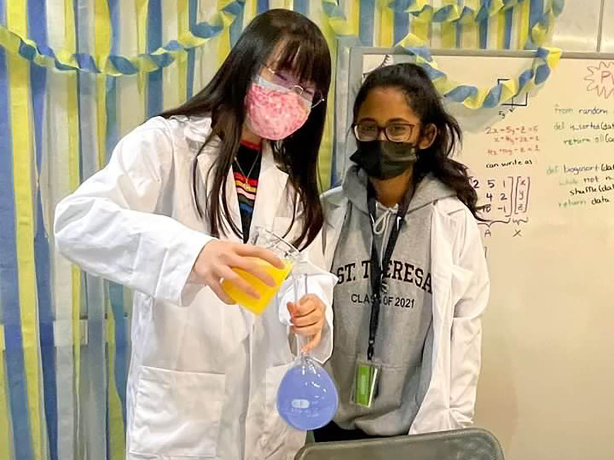 Lynn and her friend in lab coats at an ArtSci photobooth. 