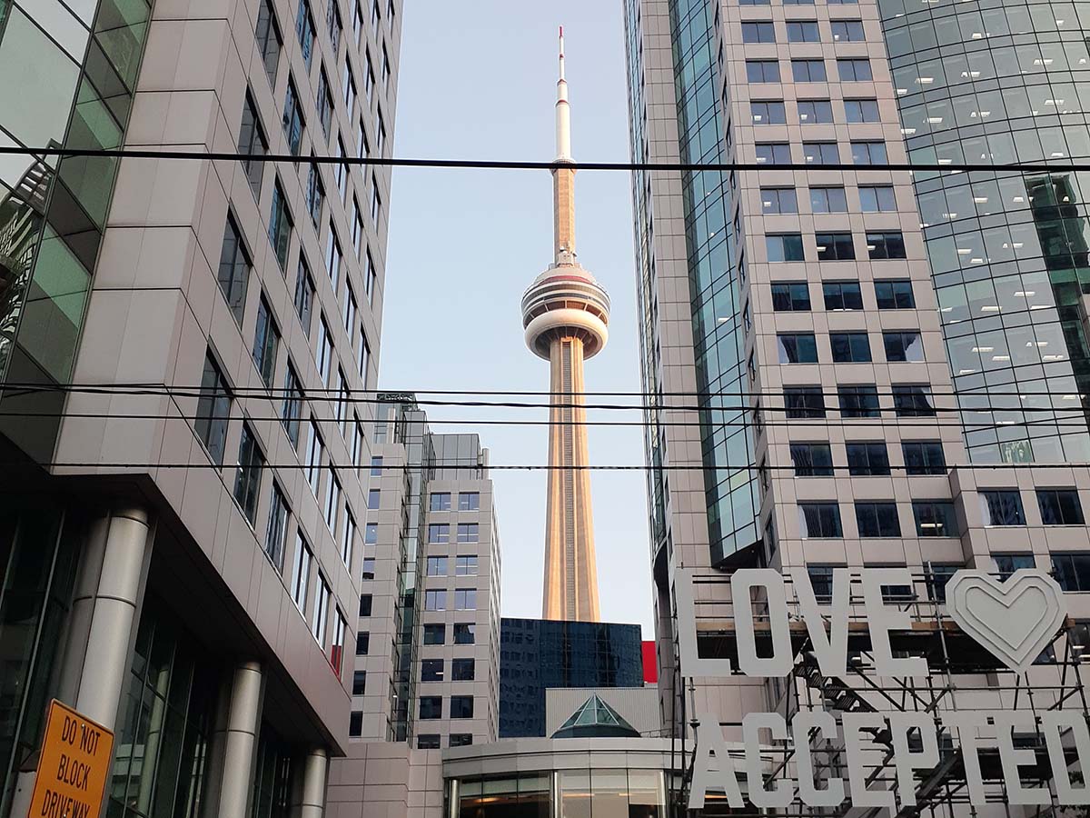 The CN Tower framed by two office buildings in front of a pale blue sky during the Toronto International Film Festival.
