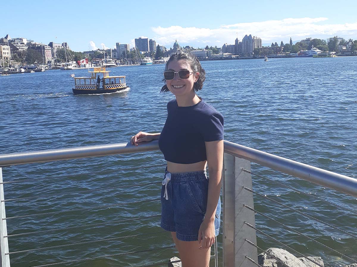 Erica smiles in front of a harbour in Victoria, British Columbia. 