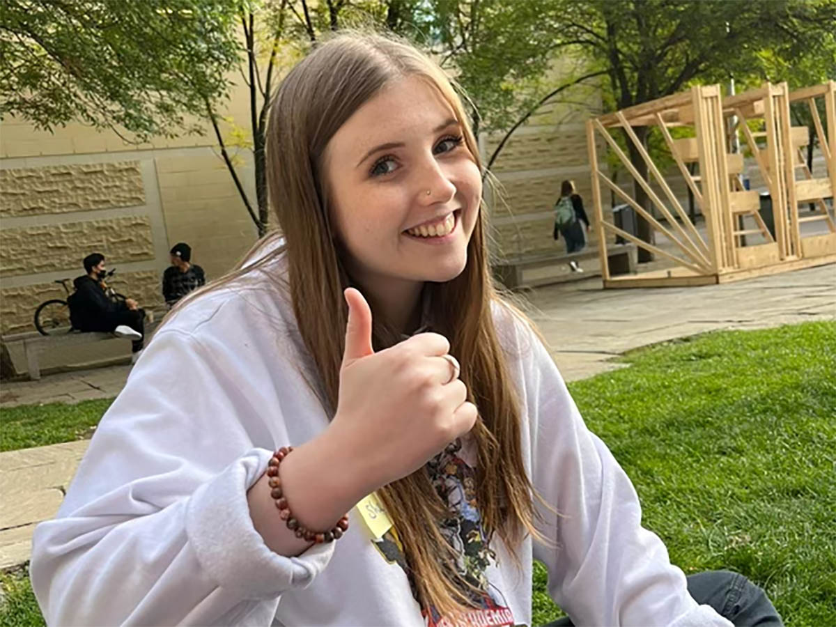 Sophie gives a thumbs-up in Pitman Quad on a sunny afternoon.