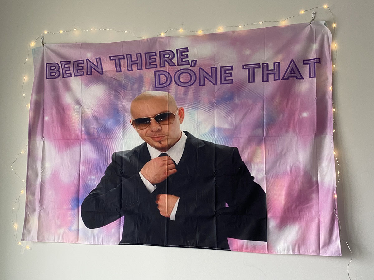 A tie-dye tapestry of the singer Pitbull with "Been there, done that" written on it.
