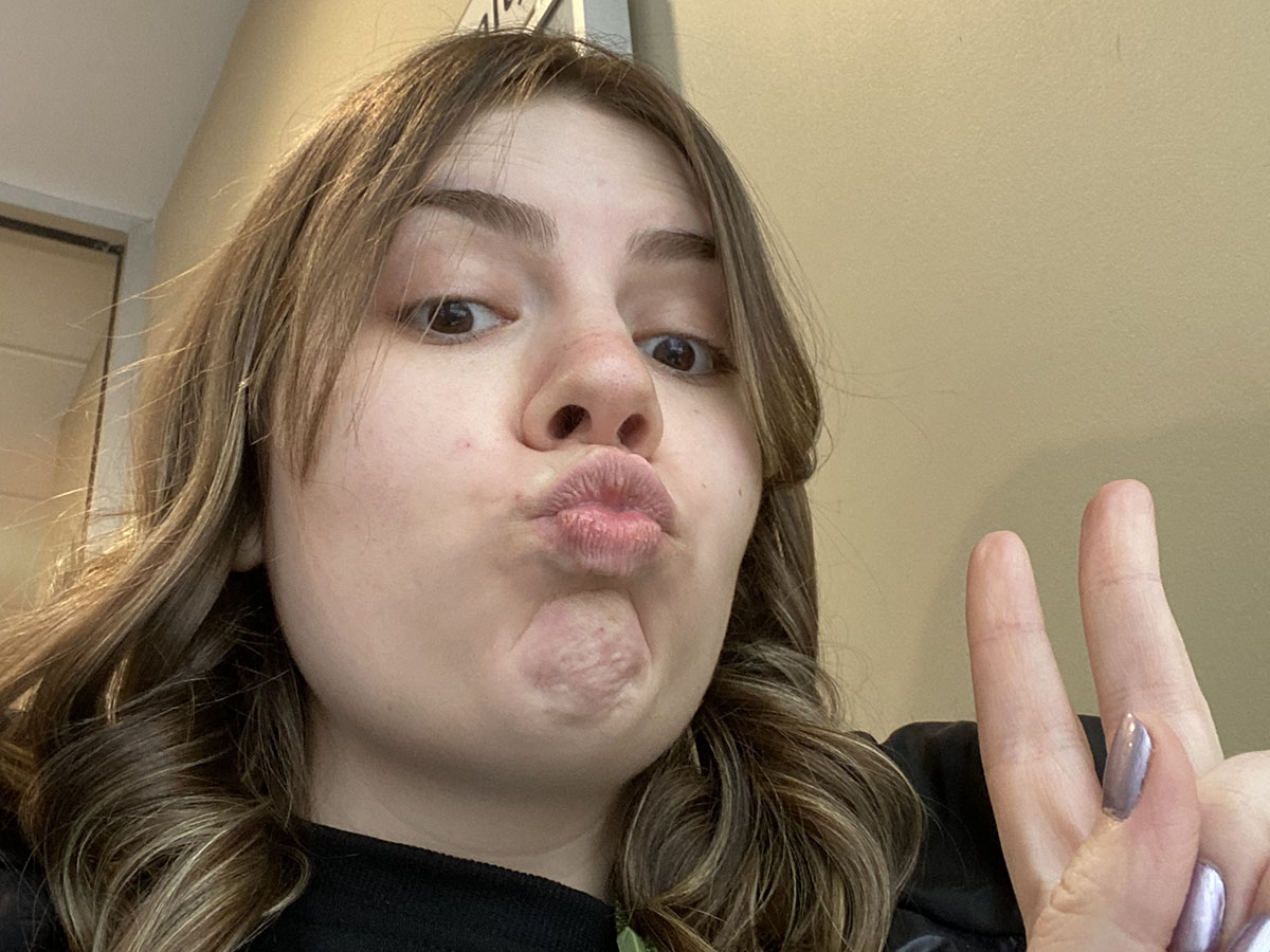 Jenna taking a selfie with her fingers in a peace sign.