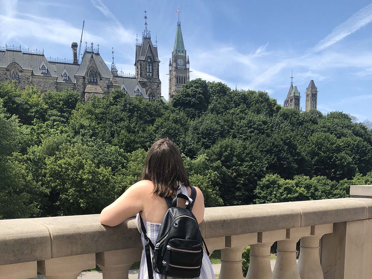 Jenna looks at the back of the Parliament buildings in Ottawa on a bright, summer day.