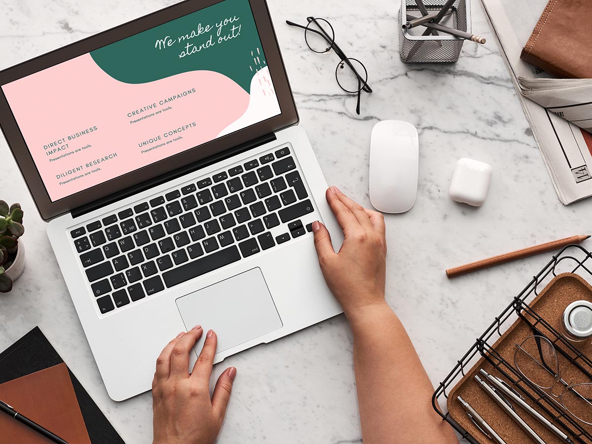 A laptop with a marketing pitch slideshow on the screen with AirPods, a mouse and other office tools beside it.