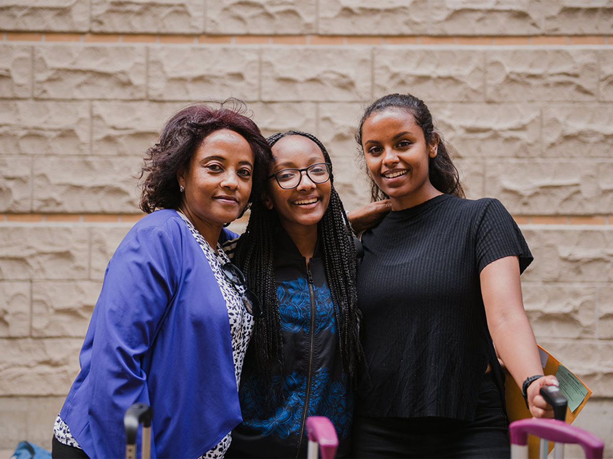 A warm group hug while looking at the camera with three individuals.