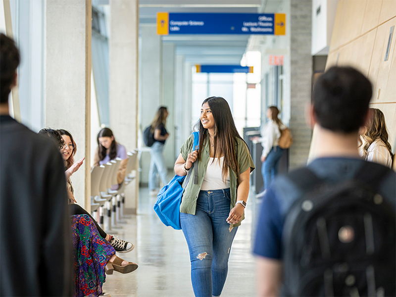 Students walking while looking out the bright windows in the Engineering building.