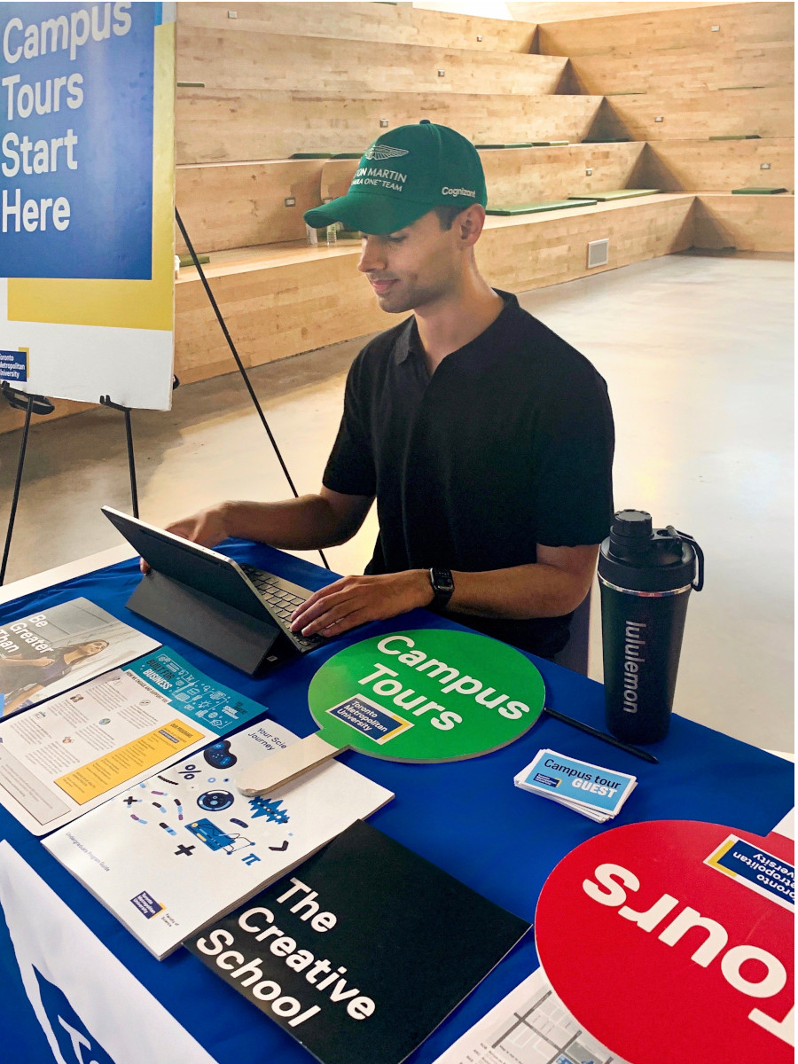 KK typing on his computer at the campus tours table