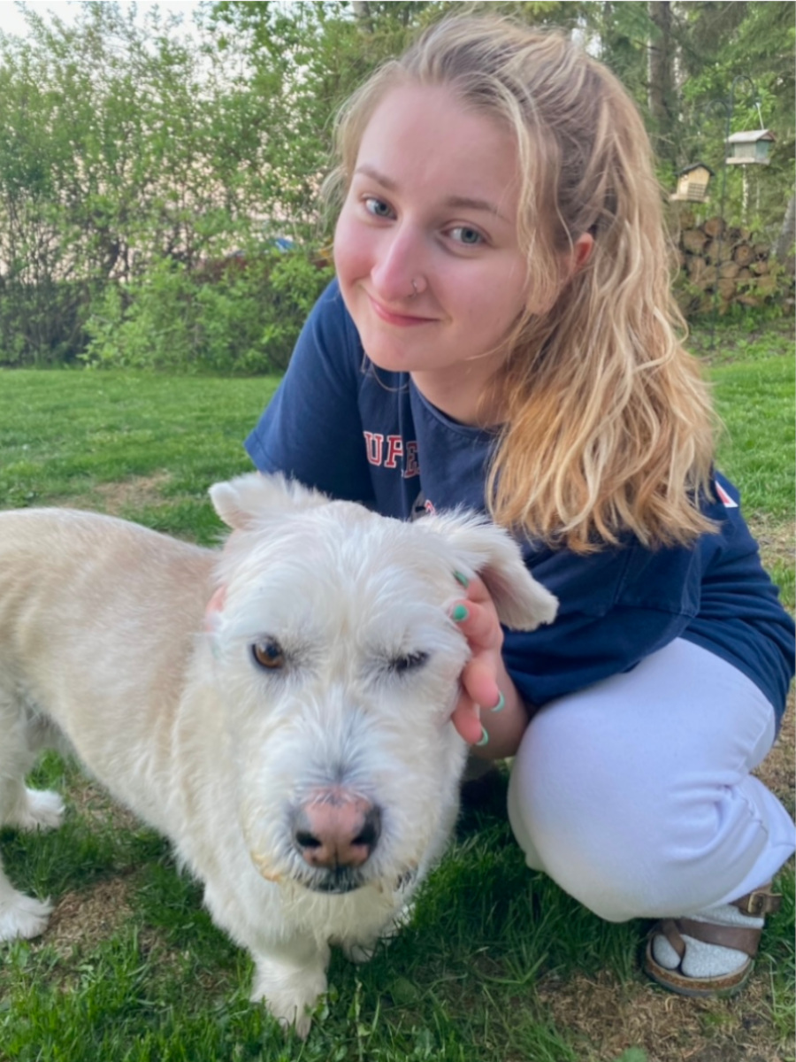 Teagan sits on grass while holding her dog