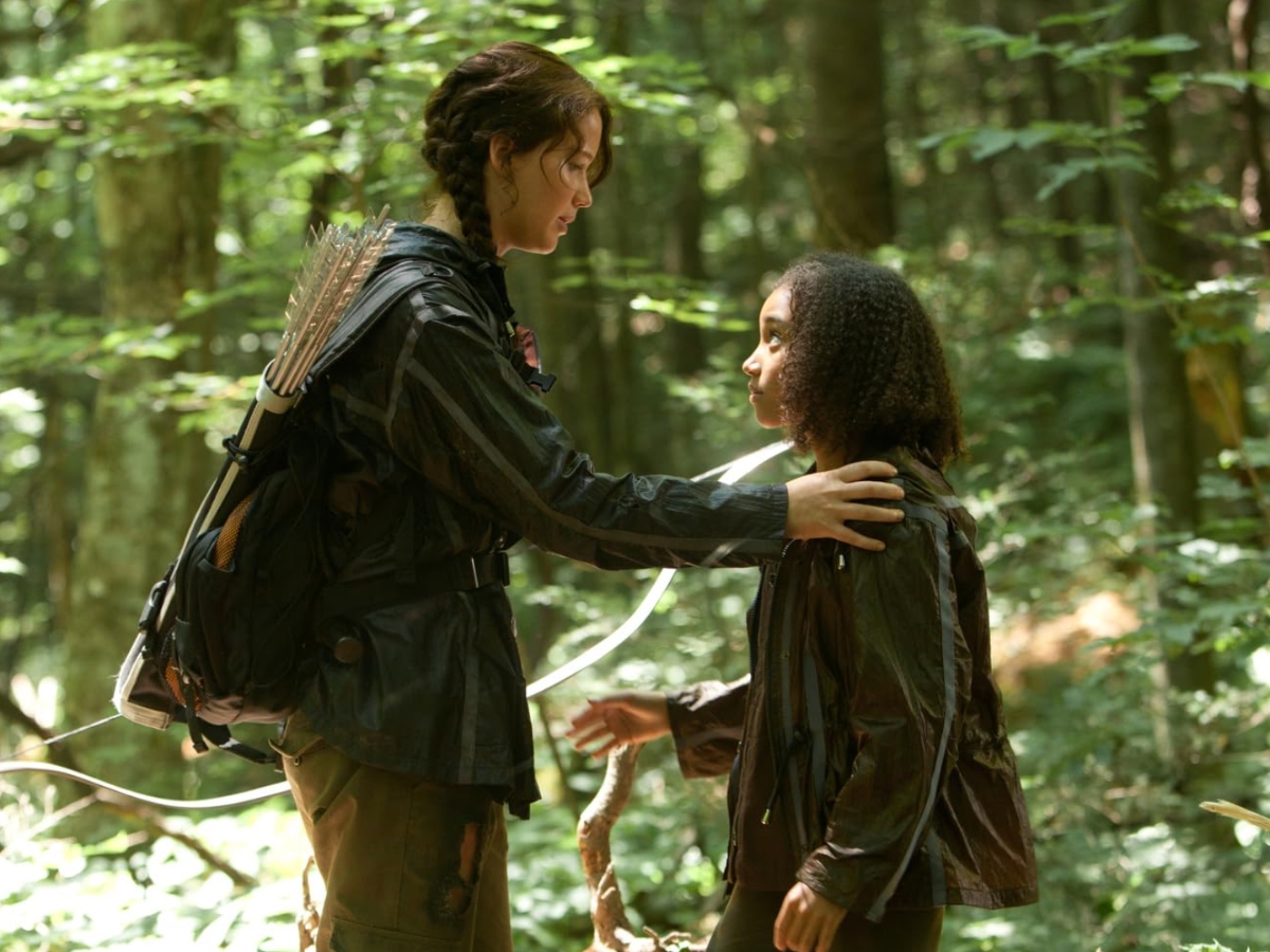 Surrounded by bright light and trees, Katniss faces Rue as she lays her hand on her shoulder.