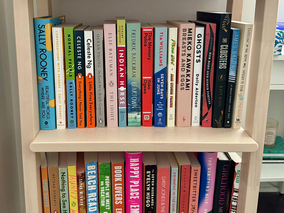 An assortment of books organized on a wooden bookshelf.