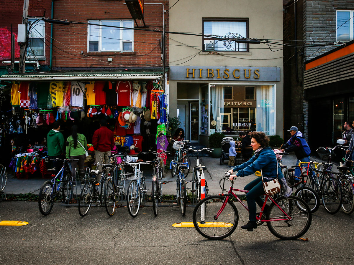 People riding their bikes and shopping in Kensington Market.