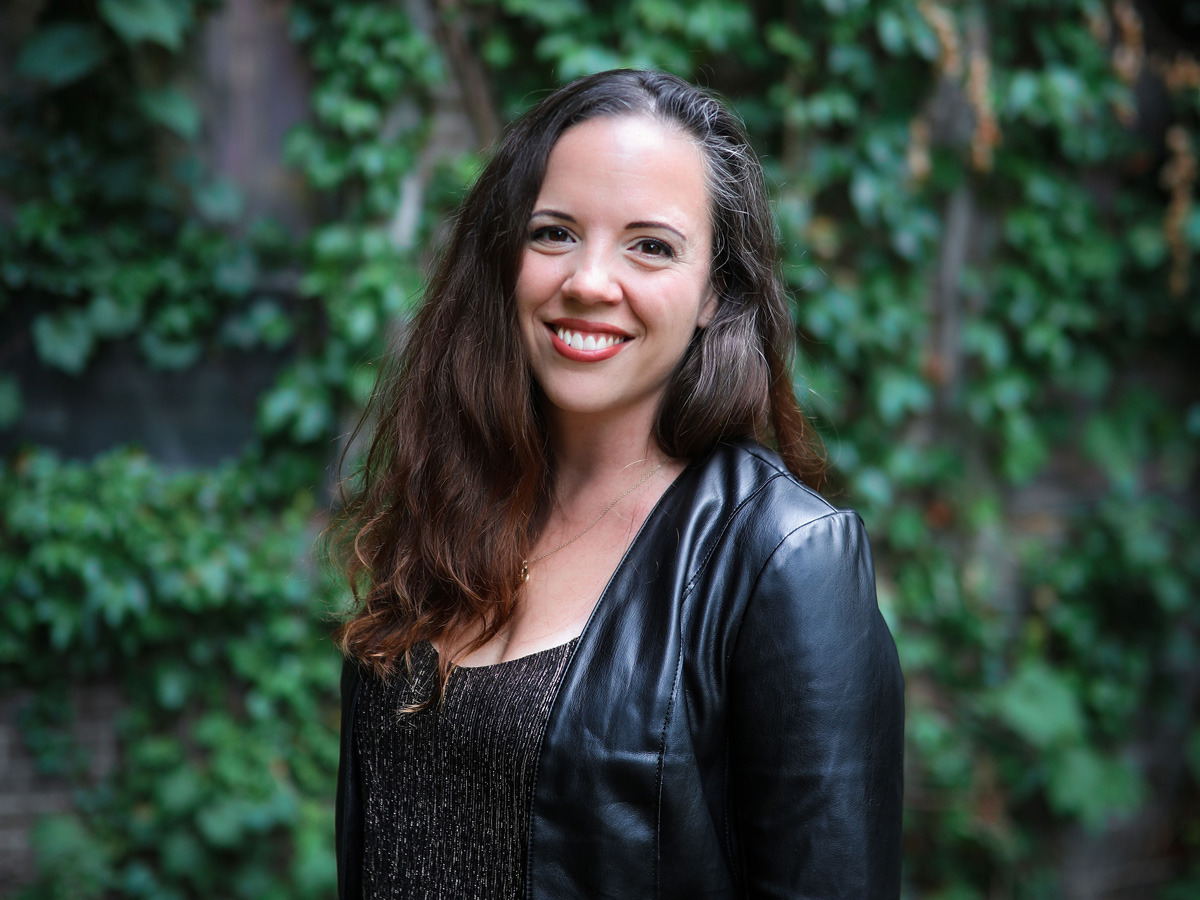 Avala smiling at the camera in front of an ivy-covered wall.