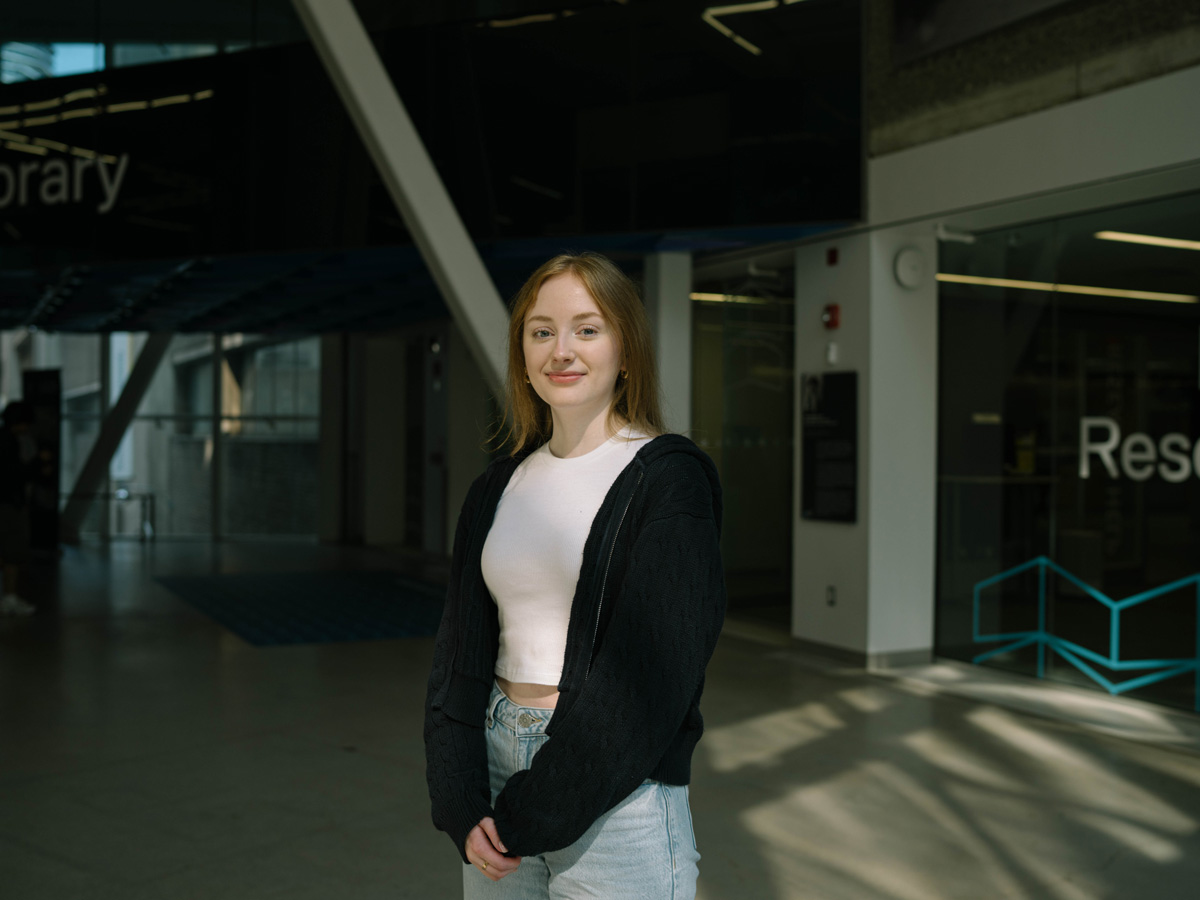Claire smiling in front of the Research Help Desk in the SLC.
