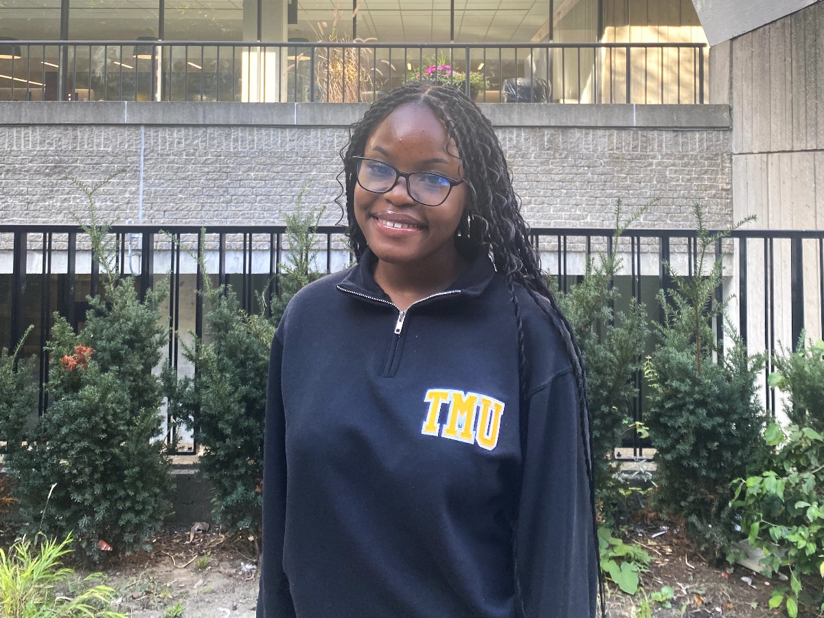 Ruth smiles on a vibrant day at TMU's campus.