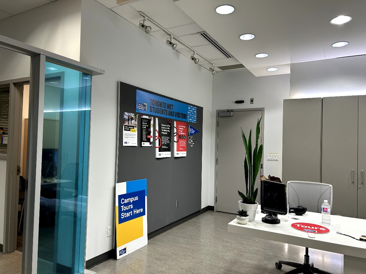Campus Tour signs sit on the desk and posters fill the walls in the Campus Tours office.