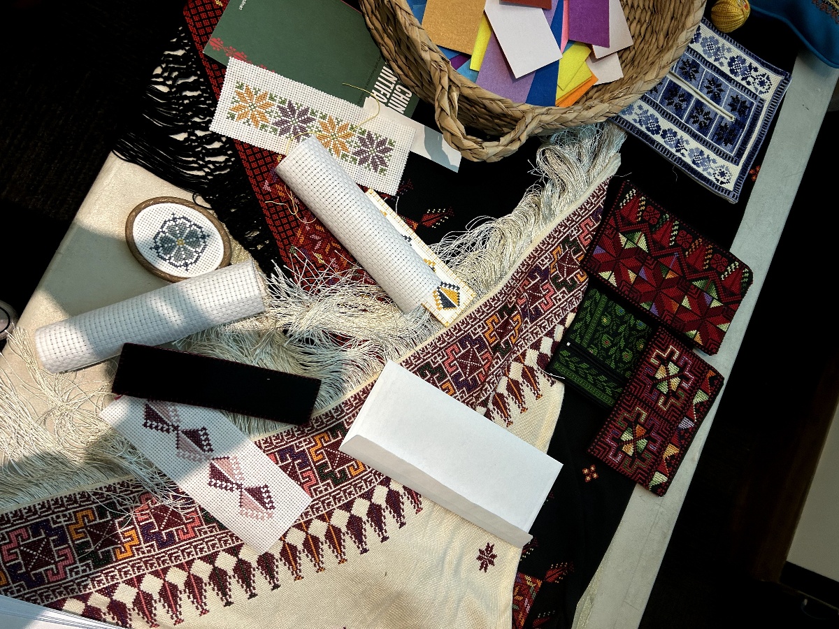 The table is filled with Palestinian embroidered bookmarks, along with fabric, thread and other craft supplies.