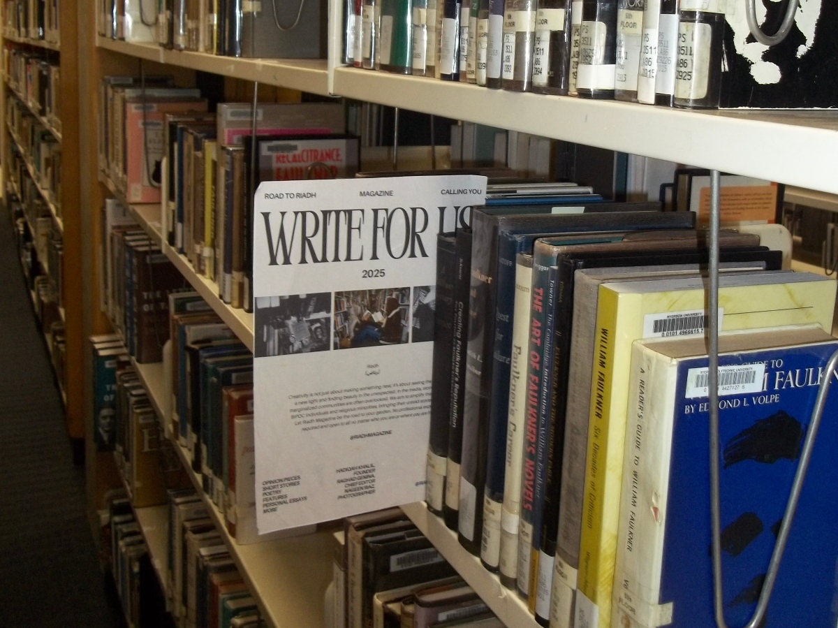 A poster saying "Write for Us" by Riadh Magazine peeks through a shelf in the TMU library.