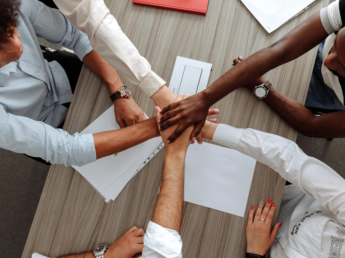 A group of colleagues holding each other's hands over a table in agreement.