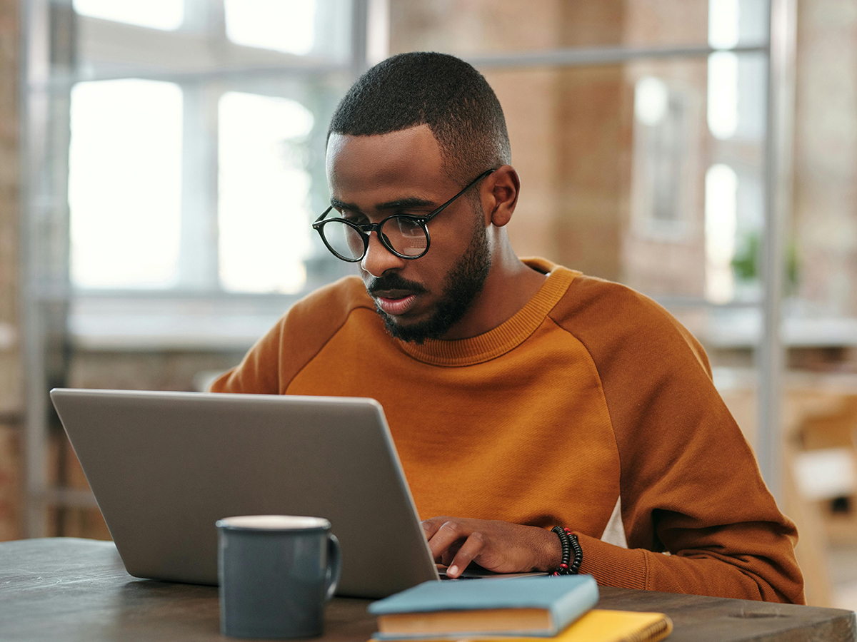 A student focused on a laptop while studying on campus.