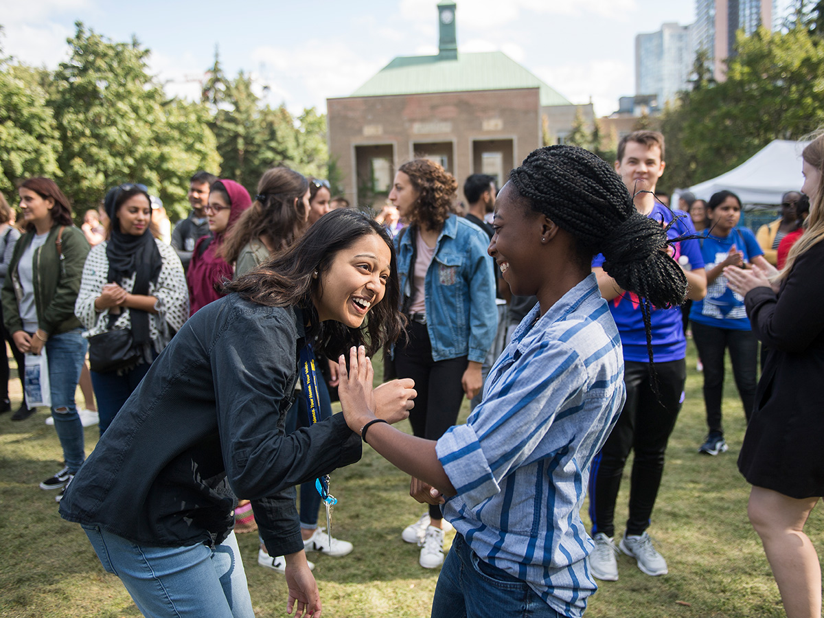 A pair of students laughing on a sunny day while participating in an Orientation activity at TMU's Kerr Quad.