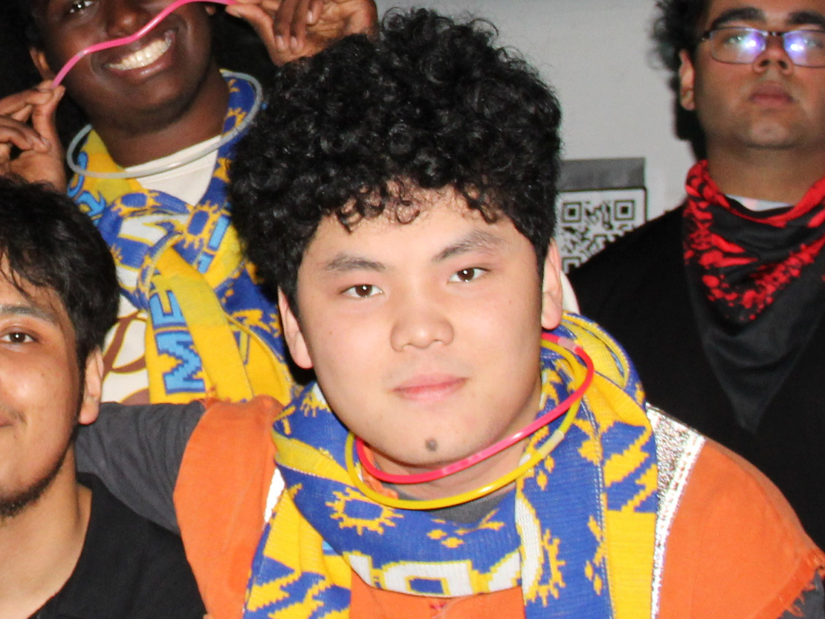 Steven poses with friends wearing matching scarves and glow stick necklaces at a TMU Engineering Frosh event. 