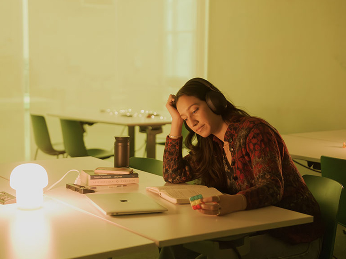 A student plays with a fidget toy at a desk and focuses on their work in the Low-Sensory Student Lounge.