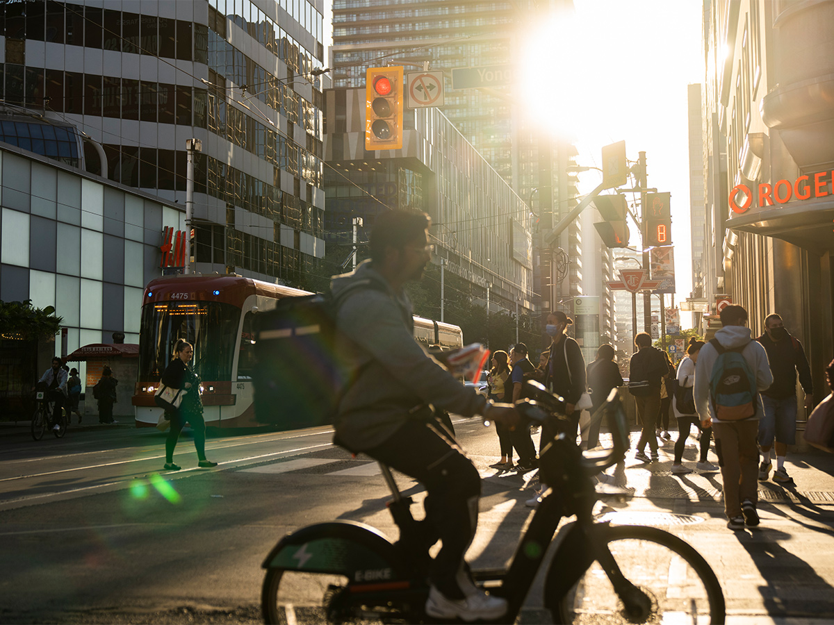 A person bikes through the busy Yonge and Dundas intersection.