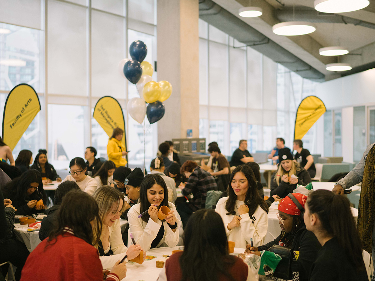 Open House guests decorate clay pots in the Student Learning Centre at a Faculty of Arts event.