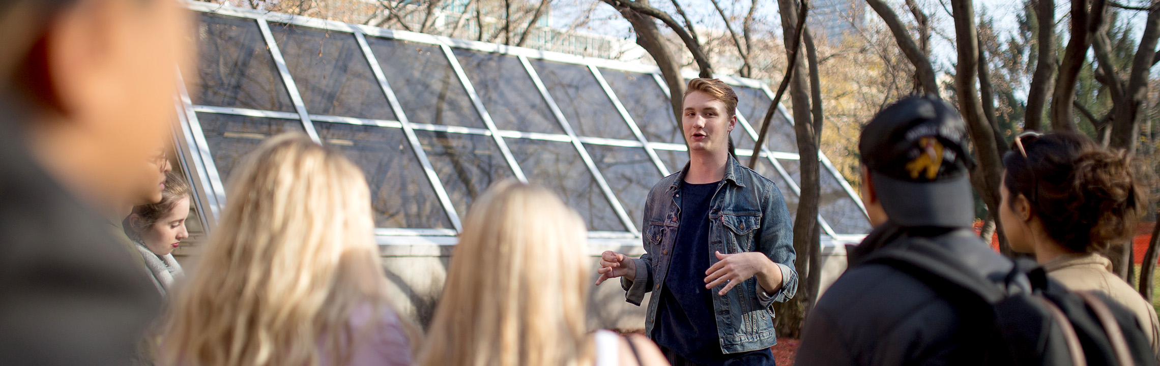 A student tour guide speaking at the Quad to guests touring the TMU campus.