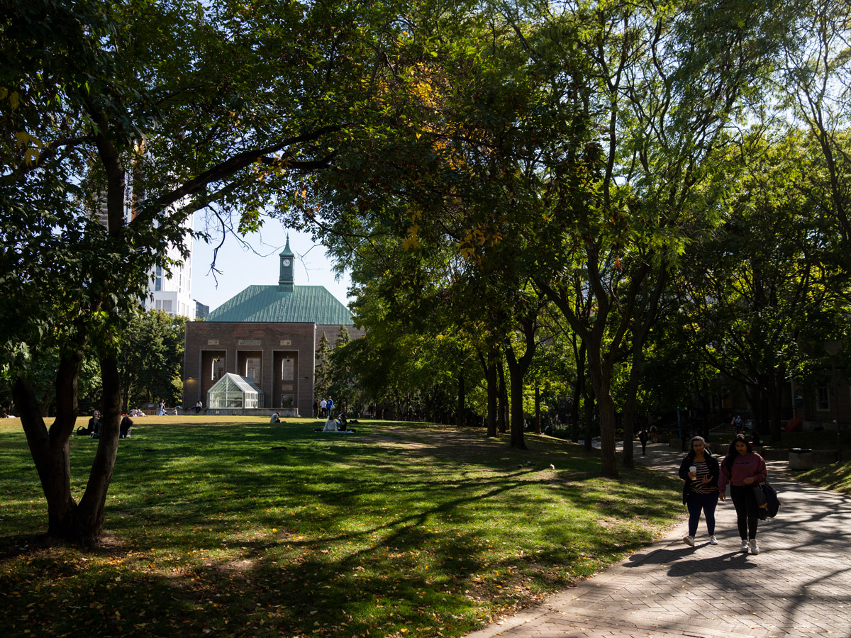 Two students walk past the Kerr Hall clock tower framed by green trees.