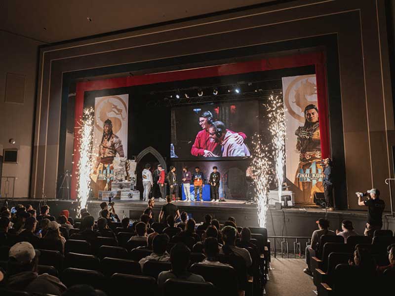 A wide shot of people standing on the stage and the audience celebrating the winners of the Mortal Kombat 1 2024 World Championship.