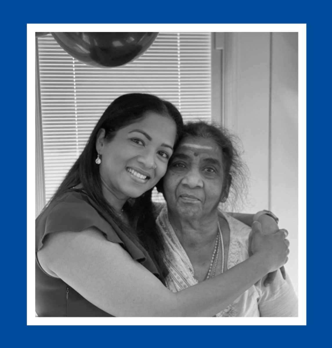 A black and white photo of a woman with her arms around an older woman. 