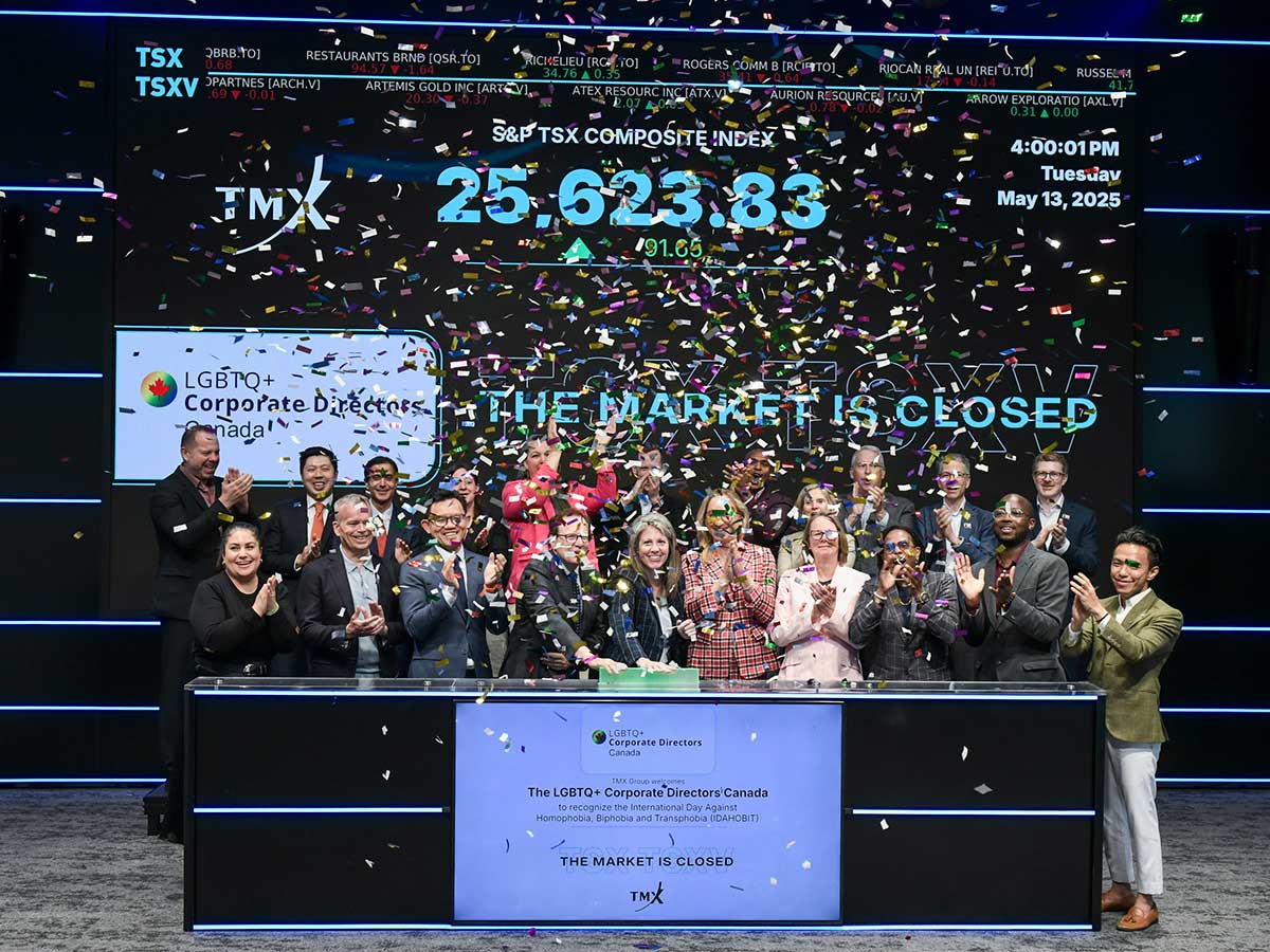 A group of business people look happy and stand at the Toronto Stock Exchange as coloured confetti falls all around them.